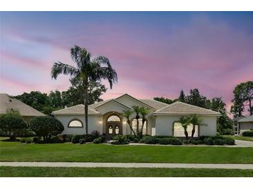Charming single-story home with lush landscaping, palm trees, and a tile roof at dusk at 216 Hammock Oak Cir, Debary, FL 32713