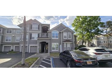 Apartment building with gray facade, covered parking, and well-maintained landscaping at 3379 S Kirkman Rd # 1015, Orlando, FL 32811