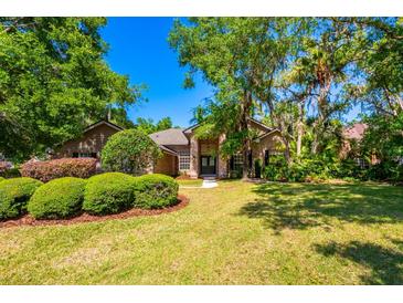 Inviting home showcasing lush landscaping with manicured bushes, mature trees, and a well-maintained lawn at 3831 River Hollow Ct, Oviedo, FL 32765
