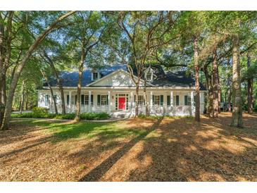 Charming home featuring a red front door and a welcoming porch with white columns, nestled among mature trees at 4000 Rouse Rd, Orlando, FL 32817