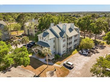 An aerial view of a well-maintained condominium complex surrounded by lush greenery and ample parking at 6178 Westgate Dr # 101, Orlando, FL 32835