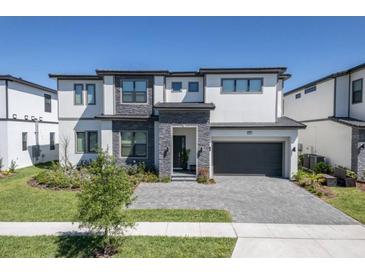 Stunning two-story home boasting modern design, stone accents, a well-manicured lawn and a gray paved driveway at 6301 Sand Skipper Rd, Orlando, FL 32821