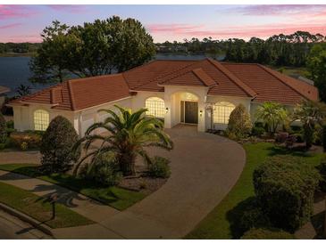 Charming single-story home featuring lush landscaping, brick driveway, and a beautiful tile roof, nestled by a serene lake at 709 Cricklewood Ter, Lake Mary, FL 32746