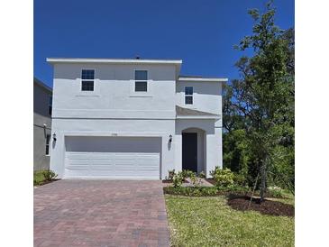 Charming two-story home with a red brick driveway, a two-car garage, and a well-manicured lawn at 1096 Happy Forest Loop, Deland, FL 32720