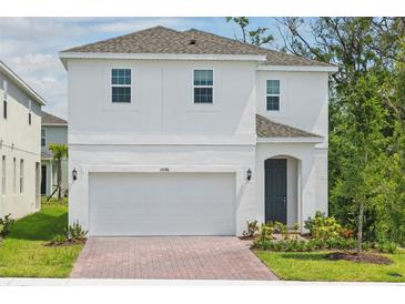 Charming two-story home featuring a two-car garage, brick driveway, and neatly landscaped front yard at 1096 Happy Forest Loop, Deland, FL 32720