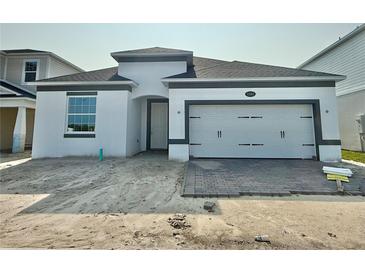 Charming single-story home with a white exterior, gray trim, brick-paved driveway, and a two-car garage at 1161 Basalt Ln, Sanford, FL 32771