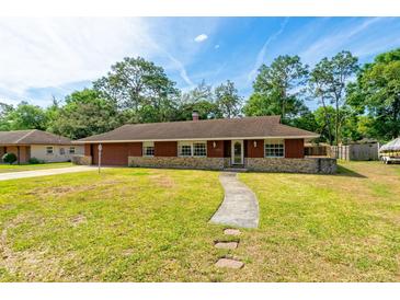 Charming single-story home with a well-maintained lawn and stone accents, providing an inviting curb appeal at 1221 Adams St, Longwood, FL 32750