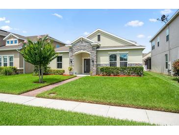 Charming single-story home with stone accents, a well-manicured lawn, and tidy landscaping at 1540 Softshell St, St Cloud, FL 34771