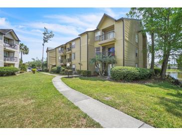 View of a well-maintained condominium building with lush landscaping and a sidewalk leading to the entrance at 1908 Lake Atriums Cir # 3, Orlando, FL 32839