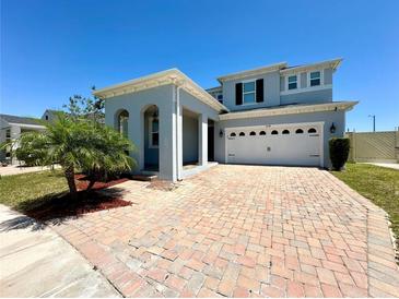 Charming two-story home features a brick driveway and attached two-car garage under a clear blue sky at 2648 Needlepoint St, Kissimmee, FL 34741