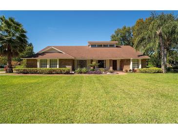 Charming brick home with a well-manicured lawn, lush landscaping, and beautiful curb appeal on a sunny day at 4464 Willow Wind Ct, Orlando, FL 32835