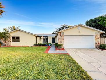 Charming single-story home features a well-manicured lawn, stone accents, and an attached two-car garage at 553 Floral Dr, Kissimmee, FL 34743