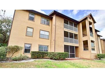 Tan condo building with screened balconies, neat landscaping and a bright, sunny sky at 627 Dory Ln # 202, Altamonte Springs, FL 32714