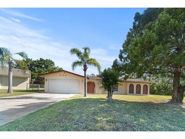 Charming single-story home featuring a manicured lawn, mature trees, and a two-car garage at 717 Wedge Ln, Kissimmee, FL 34759