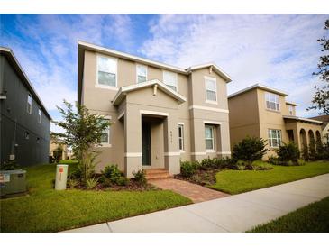 Charming two-story home featuring a well-manicured lawn, brick walkway, and neutral color palette, perfect for Gathering living at 8016 Sweet Orange Ave, Winter Garden, FL 34787