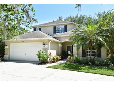 Charming two-story home featuring a well-maintained lawn, two car garage, and a welcoming entrance with a beautiful palm tree at 9573 Southern Garden Cir, Altamonte Springs, FL 32714