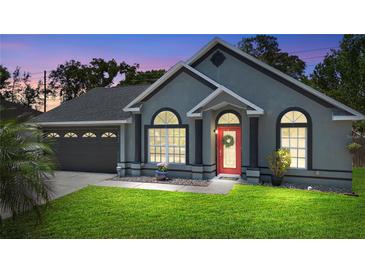 Charming single-story home featuring a red front door, a well-manicured lawn, and a two-car garage at 1848 Jimson Ave, Ocoee, FL 34761