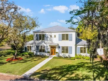 Elegant two-story home featuring a manicured lawn, blue shutters, and a light gray metal roof at 2171 Forrest Rd, Winter Park, FL 32789
