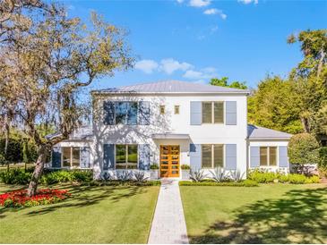 Stunning two-story home with a manicured lawn, gray metal roof and blue shutters at 2171 Forrest Rd, Winter Park, FL 32789