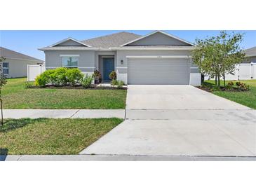 Charming single-story home with a well-manicured lawn and two car garage at 236 Aquamarine Ln, Kissimmee, FL 34758