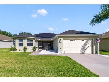 Charming home with a two-car garage, solar panels, lovely lawn, and well-kept landscaping at 26712 Augusta Springs Cir, Leesburg, FL 34748