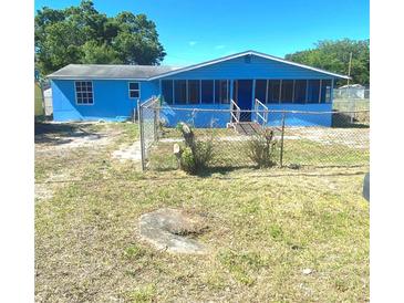 Charming blue single-story home with a screened-in porch and fenced yard under a bright blue sky at 311 E Bridgers Ave, Auburndale, FL 33823
