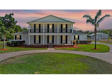 Stunning two-story home with a beautiful lawn and a circular driveway framed by classic columns and a balcony at 4232 Spring Ln, Lakeland, FL 33811