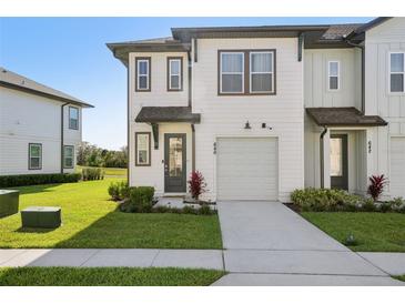 Charming townhouse with a well-maintained lawn, a private garage and walkway leading to the front door at 646 Longboat Dr, Davenport, FL 33896