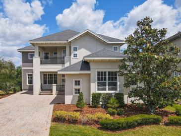 Beautiful two-story home with manicured landscaping, covered balcony, and paver driveway on a sunny day at 9421 Dugard Ct, Orlando, FL 32827