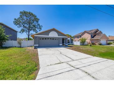 Charming single-Gathering home with a gray exterior, well-manicured lawn, and a large driveway at 1153 Perpignan Ct, Kissimmee, FL 34759