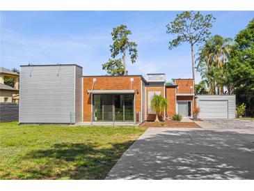 Modern home featuring wood and metal siding with manicured lawn and concrete driveway on a sunny day at 11734 Lake Willis Dr, Orlando, FL 32821