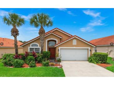 Charming single-story home with a red tile roof, lush landscaping, and a two-car garage at 119 Hypolita Ave, Davenport, FL 33897