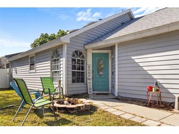 Charming single-story home featuring a cozy outdoor seating area with fire pit, and attractive blue front door at 121 Edgewater Cir, Sanford, FL 32773