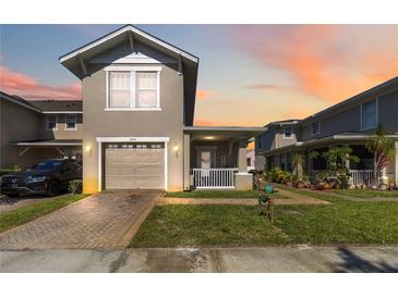 Charming two-story townhome with a well-manicured lawn, a brick driveway, and an attached garage at 2016 Cypress Bay Blvd, Kissimmee, FL 34743