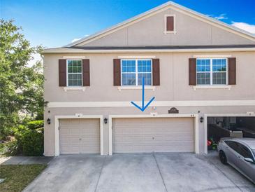 Two-story townhouse showcasing a multi-car garage, and neutral-colored exterior with well-placed windows and brown shutters at 3449 Seneca Club Loop # B, Orlando, FL 32808