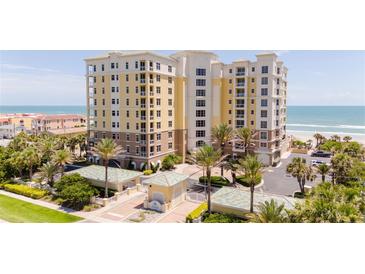 Beautiful oceanfront condominium building with palm trees and manicured landscaping, perfect for coastal living at 4071 S Atlantic Ave # 803, New Smyrna Beach, FL 32169