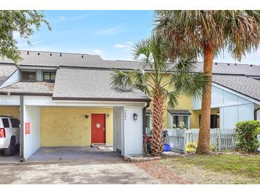 Charming townhome featuring a vibrant red front door, carport, and mature palm trees enhancing curb appeal at 7484 Canford Ct # 8, Winter Park, FL 32792