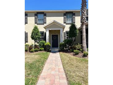 Charming townhome with a well-manicured lawn and a brick walkway leading to the front door at 7675 Fordson Ln, Windermere, FL 34786