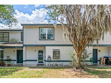 Charming townhome with covered entry, light siding, and tree in the front yard at 2652 Laser Ct, Orlando, FL 32826
