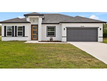 Charming single-story home featuring a gray two-car garage and a well-manicured lawn under a bright blue sky at 15046 Sw 48Th Ave, Ocala, FL 34473