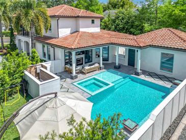 Stunning backyard featuring a pristine pool, spa, and an outdoor fireplace for relaxing and entertaining at 2614 Parkland Dr, Winter Park, FL 32789