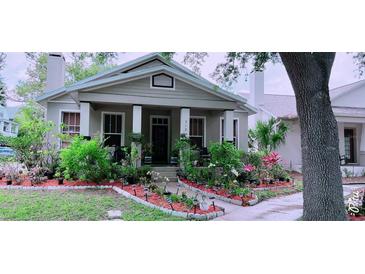 Charming single-story home with a cozy front porch and lush, colorful garden at 312 N Forest Ave, Orlando, FL 32803