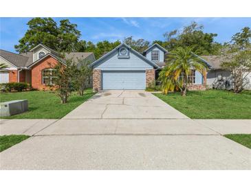 Charming blue home with a well-maintained lawn and a long driveway leading to an attached two-car garage at 212 Hound Run Pl, Casselberry, FL 32707