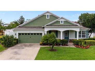 Charming single-story home featuring a well-manicured lawn, lush landscaping, and a welcoming front porch at 690 Cascading Creek Ln, Winter Garden, FL 34787