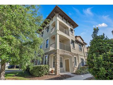 Beautiful three-story townhome with stone accents and dual balconies, enhanced by lush landscaping at 1339 Shinnecock Hills Dr, Davenport, FL 33896