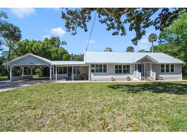 Charming single-story home with a light metal roof, well-manicured lawn, and covered parking at 1405 Pioneer Trl, New Smyrna Beach, FL 32168