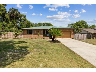 Charming brick home featuring an attached garage, green roof, and a well-manicured lawn in a desirable neighborhood at 255 Katrina St, De Leon Springs, FL 32130