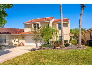 Two-story home featuring a red tile roof, attached garage, manicured lawn, and tropical landscaping on a sunny day at 2611 Albion Ave, Orlando, FL 32833