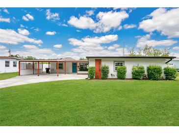 Charming single story home featuring a lush lawn, inviting curb appeal, and a covered carport at 3713 Dover St, Orlando, FL 32806