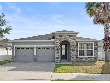Charming single-story home featuring a stone-accented entrance, gray stucco, and a well-manicured lawn at 5108 Creekside Park Ave, Orlando, FL 32811